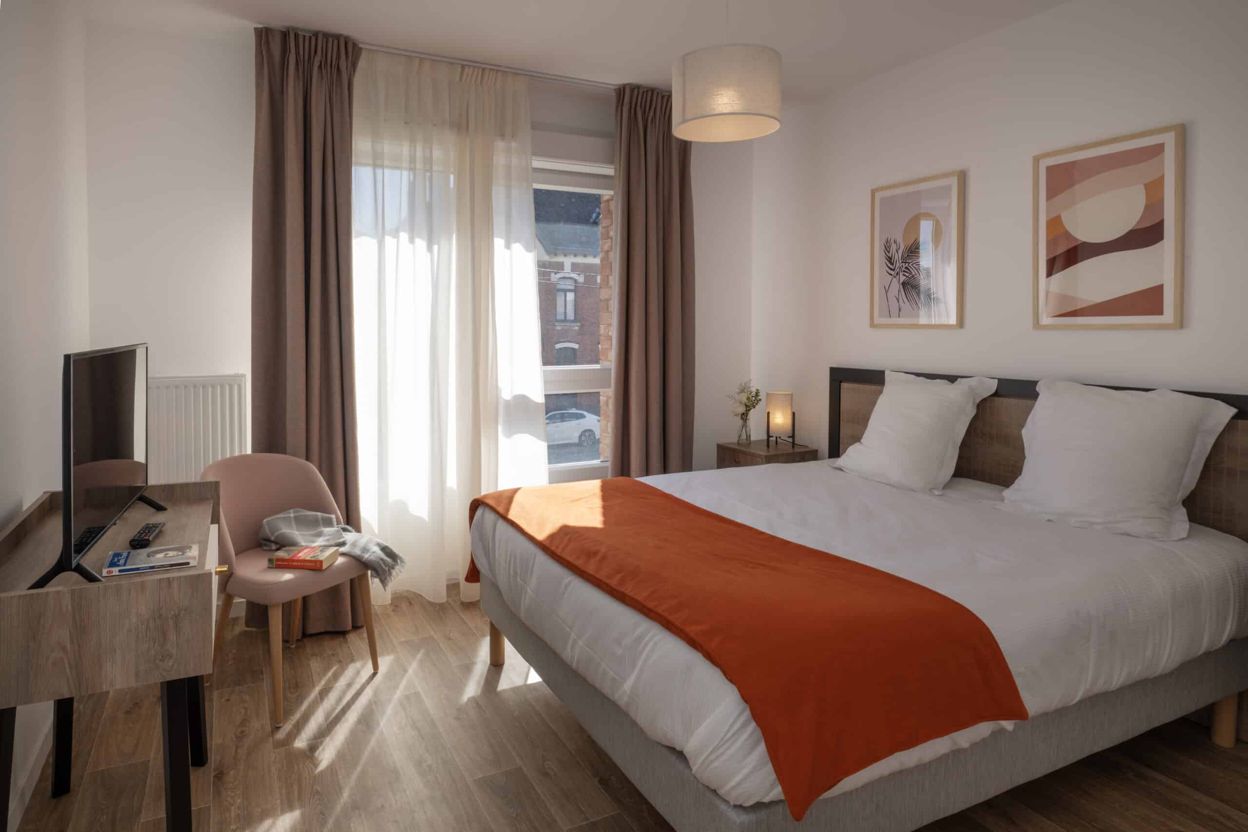 Chambre de résidence seniors équipée d'un chemin de lit terracotta, rideaux occultants, voilage sur mesure et mobilier contemporain réalisés par Norlinge.