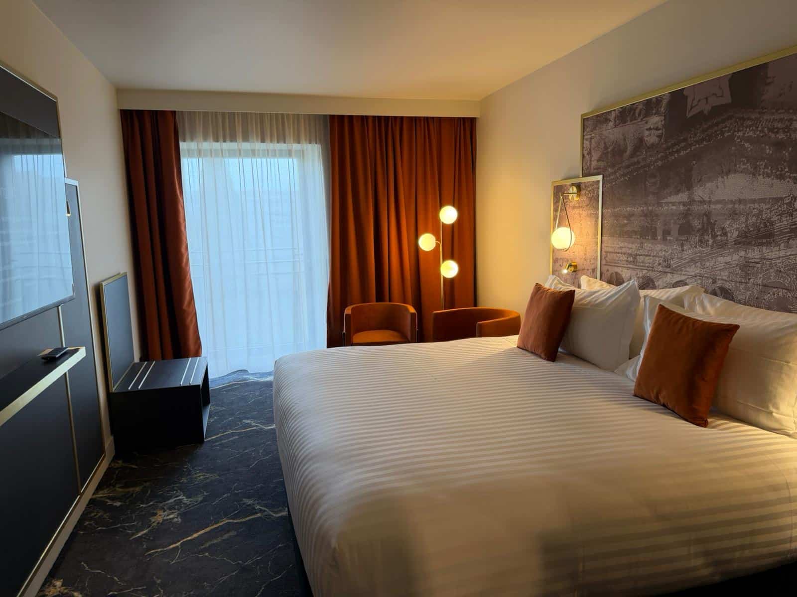Chambre double du Grand Hôtel de Nîmes avec rideaux velours terracotta sur mesure et voilages blancs posés par Norlinge