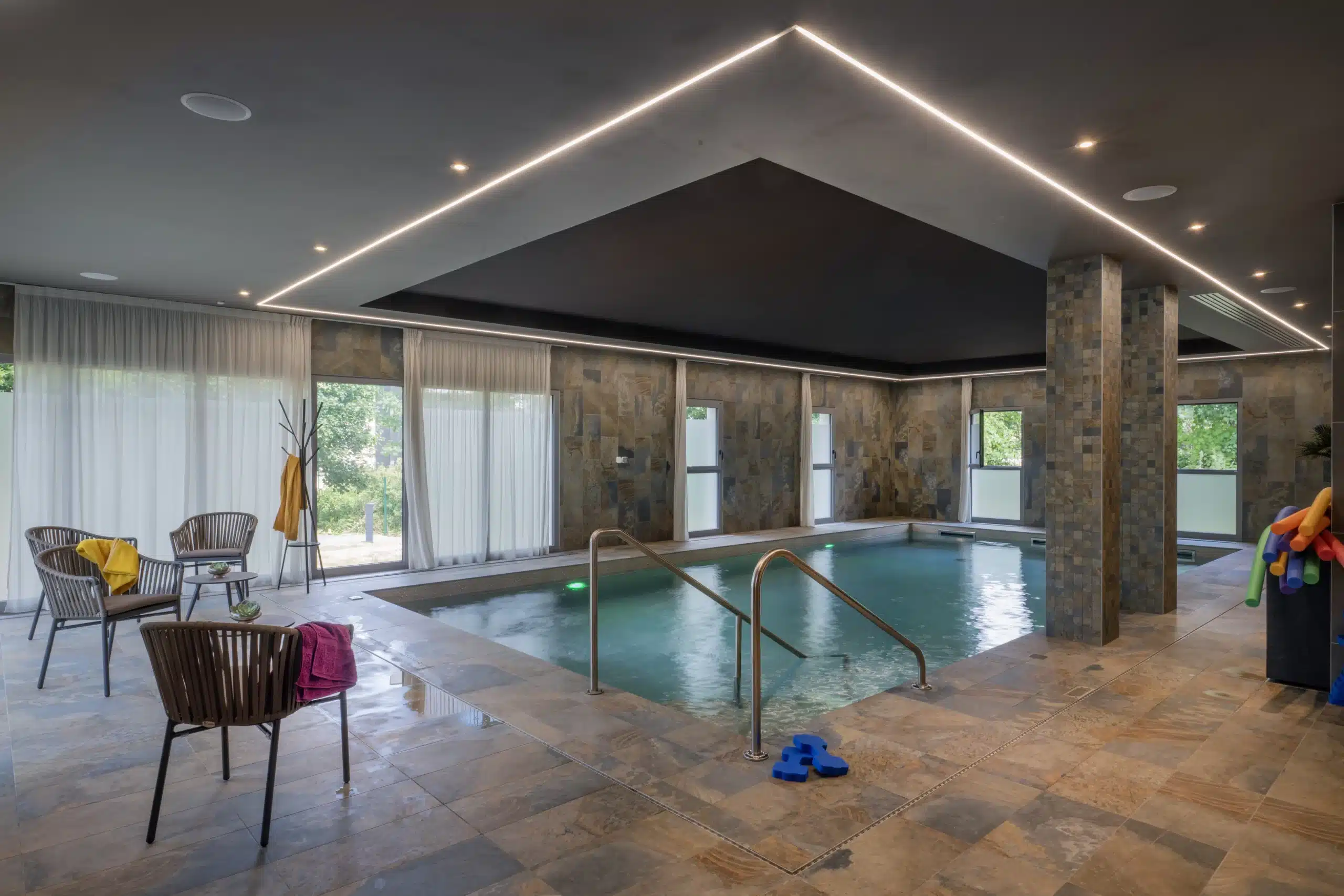 Piscine intérieure d'une résidence senior équipée de voilages sur mesure laissant entrer la lumière naturelle.