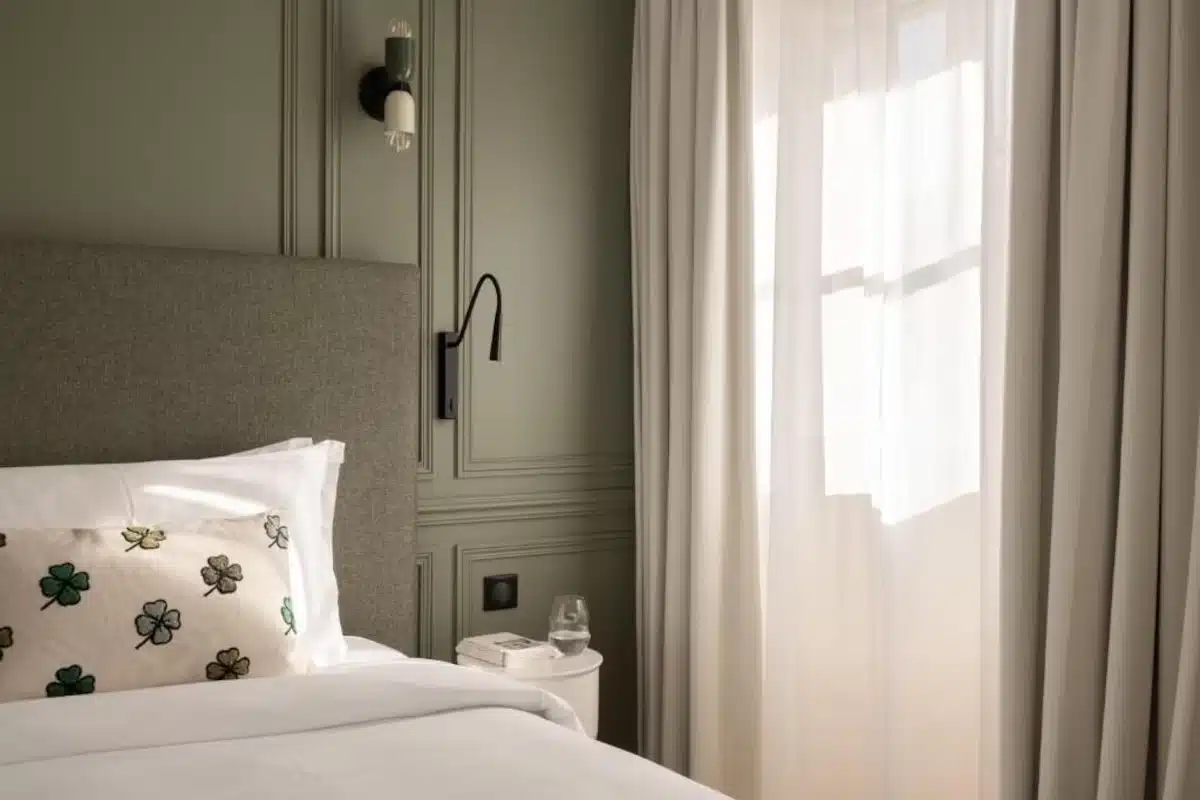 Chambre d’hôtel avec voilage blanc sur mesure et rideaux aux fenêtres